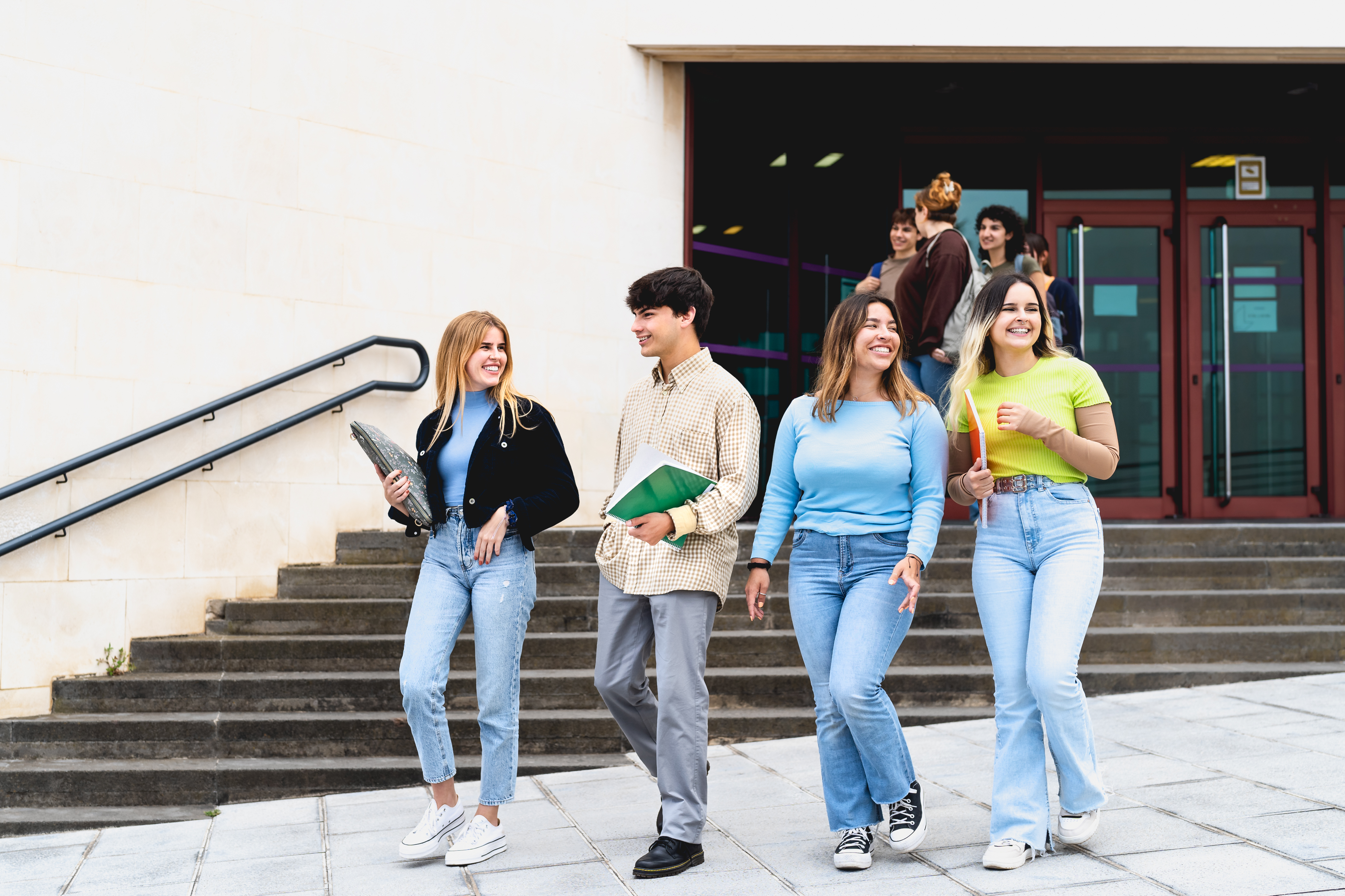 Young diverse students leaving university after lesson - Youth and education concept
